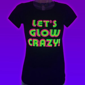 Puede incluir: Camiseta negra con el texto "LET'S GLOW CRAZY!" en verde ne&oacute;n, rosa y amarillo. El texto est&aacute; centrado en la parte delantera de la camiseta. La camiseta tiene cuello redondo y mangas cortas.