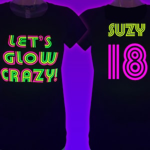 Puede incluir: Dos camisetas negras con texto de ne&oacute;n. Una dice "LET'S GLOW CRAZY!" en verde, rosa y amarillo. La otra dice "SUZY 18" en amarillo y rosa. Las camisetas se muestran en un maniqu&iacute;.