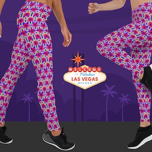 May include: A pair of leggings with a colorful geometric pattern featuring red, blue, yellow, and white circles. The leggings are worn by a person standing on a purple background with a sign that reads "Welcome to Fabulous Las Vegas, Nevada".