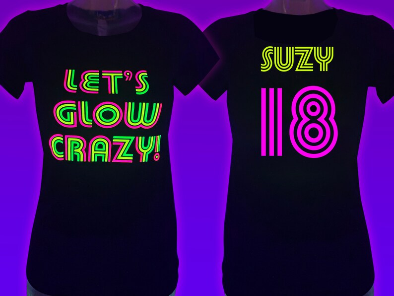 Puede incluir: Dos camisetas negras con texto de ne&oacute;n. Una dice "LET'S GLOW CRAZY!" en verde, rosa y amarillo. La otra dice "SUZY 18" en amarillo y rosa. Las camisetas se muestran en un maniqu&iacute;.