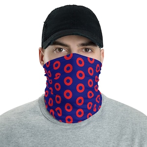 May include: A blue face mask with a repeating pattern of red donuts. The mask is worn by a person with a black baseball cap.