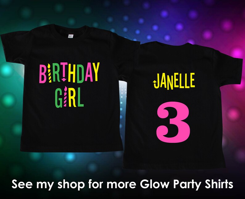 Puede incluir: Camisetas negras con texto y gr&aacute;ficos coloridos. Una camiseta dice "BIRTHDAY GIRL" en rosa, amarillo y verde con gr&aacute;ficos de velas. La otra camiseta tiene el nombre "Janelle" y el n&uacute;mero "3" en rosa.