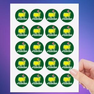 May include: A sheet of 20 round stickers featuring the Masters Tournament logo. Each sticker is green with a yellow outline of the United States and a red flag. The text "MASTERS" is printed in white below the logo.