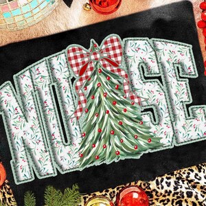 Op de afbeelding: Een zwarte decoratieve mat met het woord "NURSE" in witte letters met een groen bloemmotief. Een kerstboom met een rood-witte geruite strik staat in het midden. Rode ballen en een luipaardprint rand maken het feestelijke ontwerp compleet.