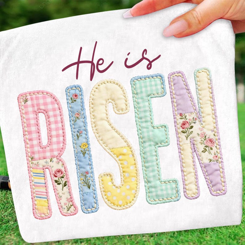 May include: A white decorative pillow with the words "He is Risen" in a script font and patchwork letters. The letters are in pastel colors and floral patterns, with a stitched border.