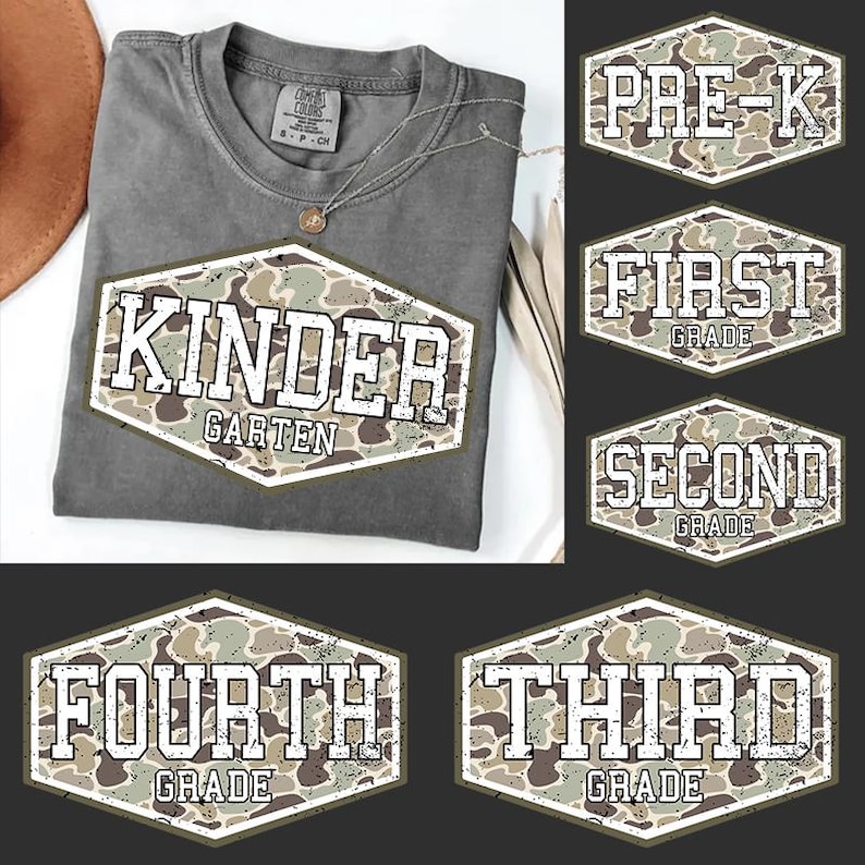 May include: A gray t-shirt with a large, distressed-style graphic that reads "KINDER GARTEN" in white letters over a camouflage pattern. Additional grade level graphics are also displayed, including "PRE-K", "FIRST GRADE", "SECOND GRADE", "FOURTH GRADE", and "THIRD GRADE".