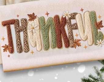 Könnte beinhalten: Ein cremefarbenes Dekohandtuch mit dem gestickten Wort "THANKFUL". Die Buchstaben weisen verschiedene Texturen und Farben auf, darunter Leopardenmuster, Strickmuster und florale Akzente, mit goldenen Verzierungen und Herbstblattdetails.