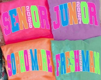 May include: Four colorful sweatshirts, each with a different class year and text. The shirts are pink, purple, orange, and green. The text on the shirts reads "SENIOR 2026", "JUNIOR 2027", "SOPHOMORE 2028", and "FRESHMAN 2029".