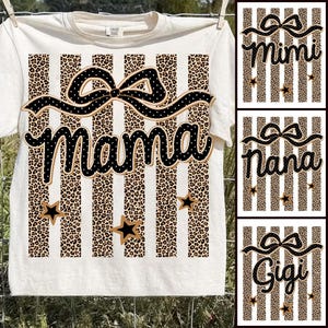 May include: Cream-colored t-shirt with vertical stripes alternating between leopard print and white. The word "Mama" is written in a black script font with a bow design above it. Additional designs include black stars.