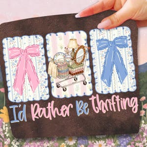 Puede incluir: Un posavasos marr&oacute;n con el texto "I'd Rather Be Thrifting". El posavasos presenta tres paneles decorativos con un lazo rosa, un carrito de compras lleno de art&iacute;culos vintage y un lazo azul. Los paneles tienen un fondo floral y a rayas.