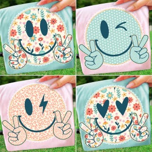 May include: Four colorful t-shirts with smiley face designs. Each shirt features a different smiley face expression, including winking, peace signs, and floral or leopard print accents. The shirts are held up by hands.