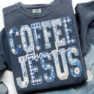 May include: A navy blue sweatshirt with the words "COFFEE And JESUS" appliqued in a patchwork style. The letters are in a collegiate font, with blue and white floral, gingham, and polka dot patterns. The sweatshirt has a crew neck and long sleeves.