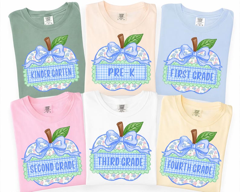 Op de afbeelding: Zes t-shirts met korte mouwen in saliegroen, perzik, lichtblauw, roze, wit en geel. Elk shirt heeft een appelafbeelding met een blauwe strik, groen blad en een blauw geblokte banner met de tekst KINDER GARTEN, PRE-K, FIRST GRADE, SECOND GRADE, THIRD GRADE of FOURTH GRADE.