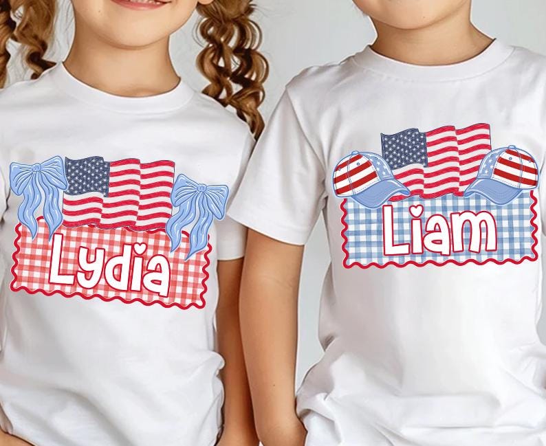 Puede incluir: Camisetas blancas con dise&ntilde;os patri&oacute;ticos. Una camiseta presenta el nombre "Lydia" con lazos azules y una bandera americana. La otra camiseta tiene el nombre "Liam" con gorras de b&eacute;isbol y una bandera americana.