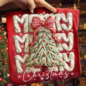 May include: A red Christmas pillow with the words "MERRY CHRISTMAS" embroidered in white. A green and white Christmas tree with red ornaments and a red bow is in the center of the pillow.