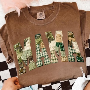 Op de afbeelding: Een set van drie keramische mokken met een gespikkelde, matte afwerking. De mokken zijn in crème, lichtgrijs en donkergrijs. Elke mok heeft een eenvoudig, minimalistisch ontwerp.