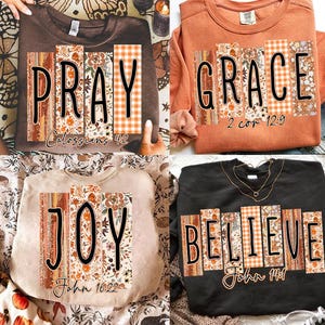 May include: Four sweatshirts with the words "PRAY", "GRACE", "JOY", and "BELIEVE" in a decorative font. Each word is designed with a combination of floral, wood grain, and plaid patterns. The sweatshirts are in brown, orange, beige, and black.