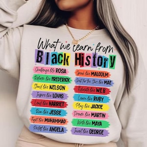 May include: A white sweatshirt with the text "What we learn from Black History" in a colorful design. The names of historical figures are listed below the title, each on a colored banner.