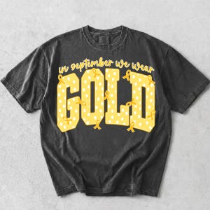 May include: A charcoal grey short-sleeve t-shirt featuring the yellow text "in september we wear GOLD" in a block font. The letters are filled with a white polka dot pattern and decorated with small yellow awareness ribbons throughout the design.