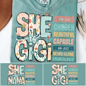 May include: A teal blue t-shirt with a floral design that says "She is Gigi" with a list of bible verses and words like "Strong", "Chosen", "Beautiful", "Capable", "Victorious", "Never Alone", and "Greatly Loved".