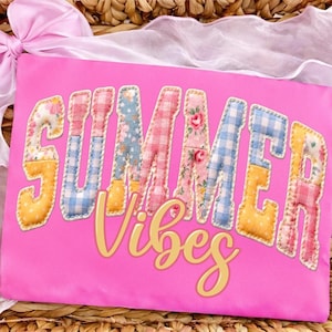 Puede incluir: Una funda de almohada rosa brillante con las palabras "SUMMER Vibes" en un estilo patchwork. Las letras están rellenas de patrones florales, de cuadros y lisos en amarillo, azul y rosa. La funda de almohada está sobre un fondo tejido.