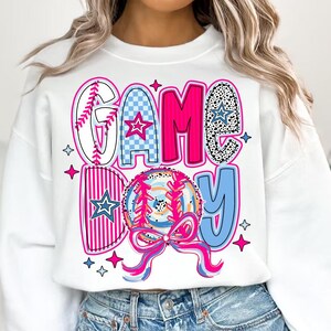 May include: White sweatshirt with a pink, blue, and white graphic design that says "GAME DAY" with a baseball and stars.