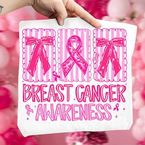 May include: White tote bag with a pink Breast Cancer Awareness design. The design includes pink ribbons, bows, and the words "Breast Cancer Awareness" in a decorative font. The background features pink and white stripes.