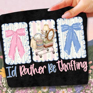 Puede incluir: Alfombra decorativa negra con tres im&aacute;genes enmarcadas. Las im&aacute;genes presentan un lazo rosa, un carrito de compras lleno de art&iacute;culos vintage y un lazo azul. El texto "I'd Rather Be Thrifting" est&aacute; escrito en la parte inferior.