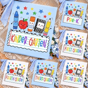 May include: A light blue fabric panel featuring a colorful embroidered design of a blue crayon, red apple, orange glue stick, black and white composition notebook, and yellow pencil above a lined paper graphic with the text KINDER GARTEN.