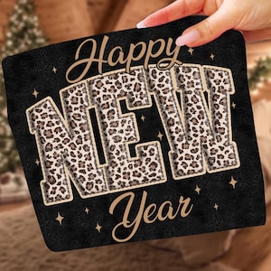 K&ouml;nnte beinhalten: Schwarzes Quadrat mit den Worten "Happy NEW Year" in goldener Schrift. Die Buchstaben "NEW" sind mit einem braunen und beigefarbenen Leopardenmuster gef&uuml;llt. Kleine goldene Sterne sind um den Text herum verstreut.
