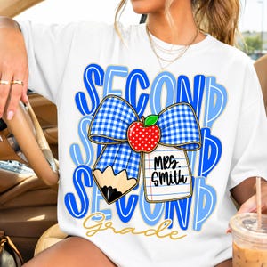 Pu&ograve; includere: T-shirt bianca con fiocco a quadretti blu e bianco, una mela rossa e una grafica a matita. Le parole "SECOND GRADE" sono in blu, con "Mrs. Smith" su un blocco note. La parola "Grade" &egrave; dorata.