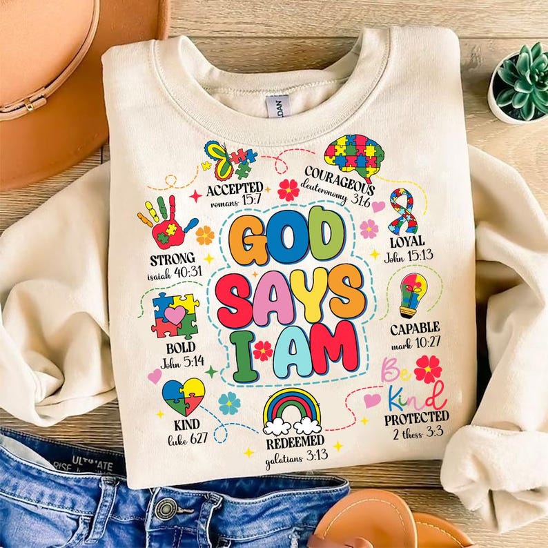 May include: A beige sweatshirt with a colorful graphic design that says "God Says I Am" with bible verses and words like "Strong", "Bold", "Kind", "Loyal", "Capable", "Protected", "Redeemed", "Courageous", and "Accepted".