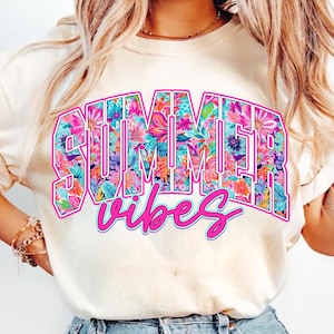 K&ouml;nnte beinhalten: Ein wei&szlig;es T-Shirt mit einem floralen Druck, auf dem in rosa Buchstaben "SUMMER vibes" steht.