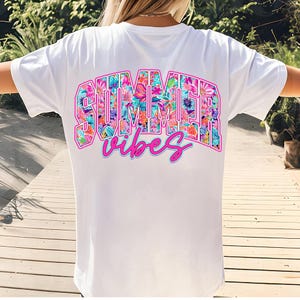 K&ouml;nnte beinhalten: Wei&szlig;es T-Shirt mit einem floralen Druck, auf dem hinten "SUMMER vibes" steht.