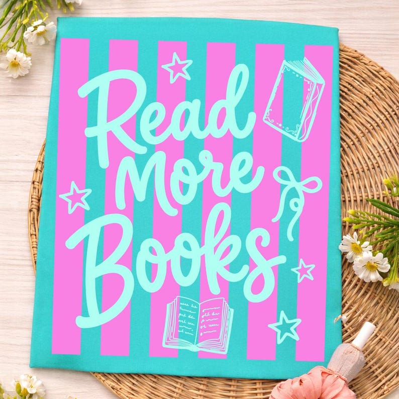 Peut inclure: Un carr&eacute; d&eacute;coratif &agrave; rayures turquoise et roses avec l'inscription "Read More Books" dans une police fantaisiste. Le motif comprend des &eacute;toiles et des illustrations de livres. Le carr&eacute; est pos&eacute; sur une surface tiss&eacute;e avec des accents floraux.