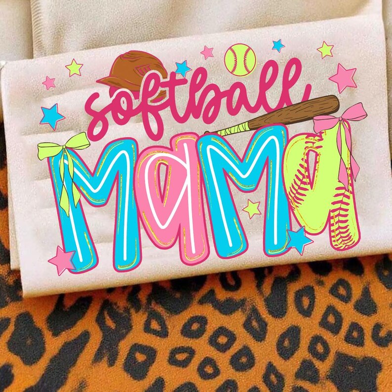 May include: A light-colored rectangular item with the words "softball MAMA" in pink and blue, decorated with a baseball bat, ball, and stars. The item is decorated with a baseball bat, ball, and stars. The background is a leopard print.