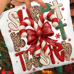 以下が含まれることがあります： 「Sweet but Twisted」の文字が様々なフォントとテクスチャで描かれた、クリスマスをテーマにした白いクッション。赤と白のキャンディケーンとキラキラ光る赤いリボンが特徴です。緑とヒョウ柄のディテールがアクセントになっています。