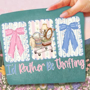Puede incluir: Camiseta gr&aacute;fica color turquesa con la frase "I'd Rather Be Thrifting". El dise&ntilde;o presenta un lazo rosa, un carrito de compras lleno de art&iacute;culos vintage y un lazo azul. El fondo tiene un estampado floral.