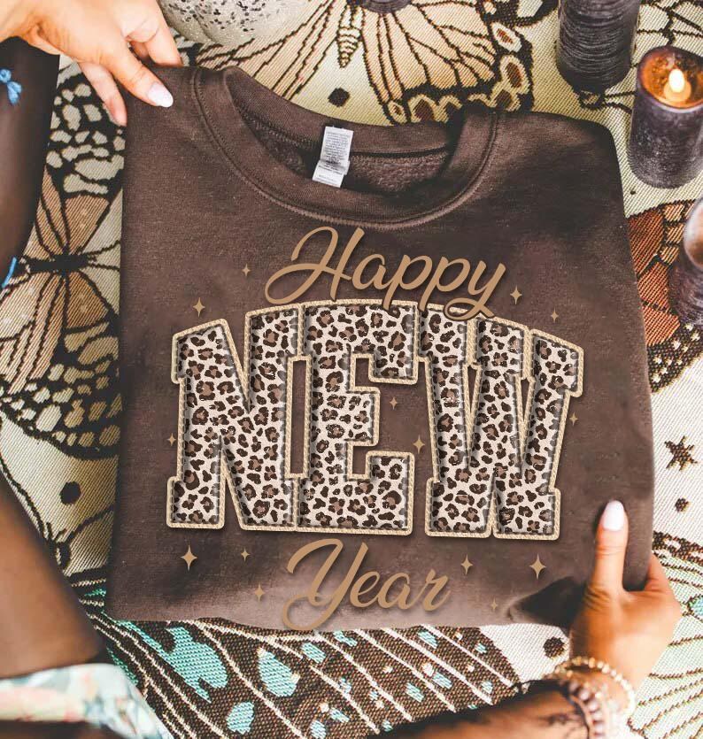 K&ouml;nnte beinhalten: Ein braunes Sweatshirt mit dem Schriftzug "Happy NEW Year" in Gold und Leopardenmuster. Das Sweatshirt wird von H&auml;nden gehalten. Das Design ist festlich und feiert das neue Jahr.