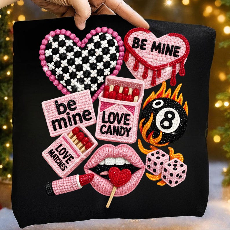 May include: Black decorative pillow featuring various rhinestone-studded designs. Includes a heart with a checkerboard pattern, a heart with "BE MINE", a cigarette box with "LOVE CANDY", a lipstick, lips with a heart lollipop, dice, and a flaming 8-ball.