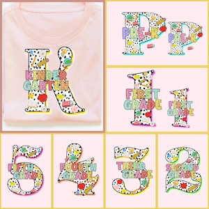 May include: A light pink t-shirt with a large letter "K" featuring the words "Kindergarten" in colorful letters. Additional images show "Pre-K", "First Grade", and numbers 2-5 with grade level text, all in a similar style.