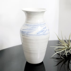 May include: White ceramic vase with a blue and white swirl design. The vase has a rounded base and a narrow neck.