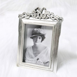 Könnte beinhalten: Silberner Bilderrahmen mit einem verzierten Design und einem Schwarzweißfoto einer Frau mit Hut. Das Foto ist mit "Größe: 3,5" x 5" beschriftet.