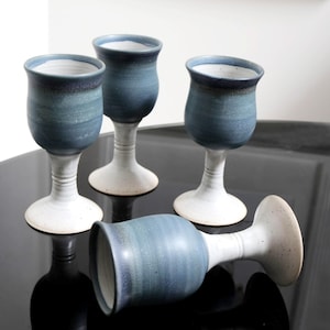 May include: Set of four blue and white ceramic goblets with a speckled glaze. The goblets have a wide bowl and a tall, slender stem.