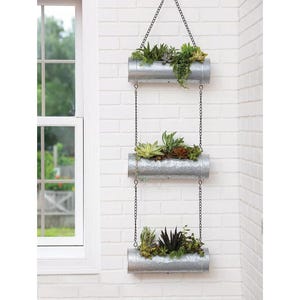 May include: Three galvanized metal hanging planters with chains, each filled with succulents. The planters are stacked vertically, with the top planter hanging from the ceiling.