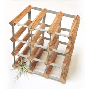 May include: A wooden wine rack with a metal frame. The rack is made of light brown wood and has a grid-like structure designed to hold multiple bottles. An air plant is placed in the rack.
