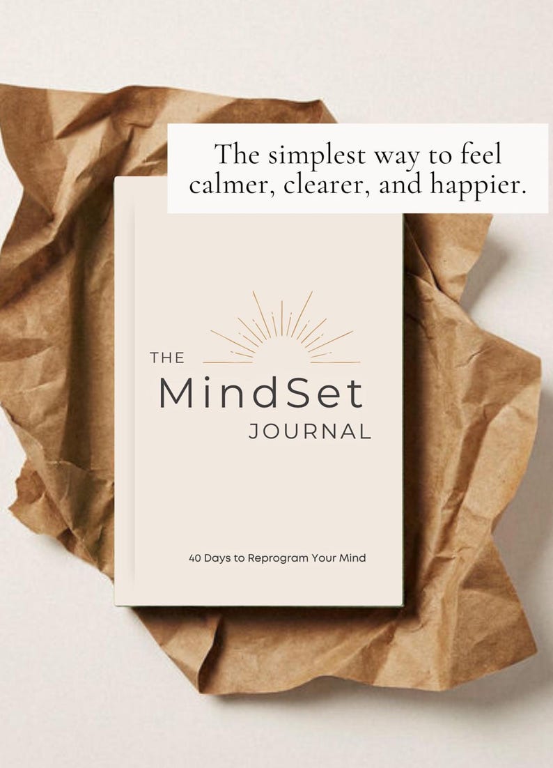 May include: A cream-coloured journal titled "The Mindset Journal" with the text "40 Days to Reprogram Your Mind." The journal is on brown paper with the text "The simplest way to feel calmer, clearer, and happier."