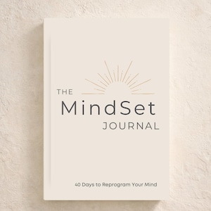 May include: A cream-coloured journal titled "The MindSet Journal" with gold accents and text that reads "A Daily Journal for Clarity & Reflection" and "40 Days to Reprogram Your Mind". The cover features a sunburst design.