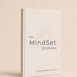 May include: A cream-coloured hardcover journal titled The MindSet JOURNAL with a gold sunburst graphic above the text. The cover includes the subtitle 40 Days to Reprogram Your Mind printed in small black lettering near the bottom of the front cover.