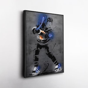May include: Framed artwork of a hockey player in action, presented in grayscale with neon blue highlights. The player is captured mid-play, wielding a hockey stick, with splashes of colour enhancing the visual appeal. The artwork is set against a textured grey backdrop.